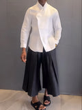 White asymmetric front long sleeve shirt and black pleated trousers co-ordinates set on a hanger