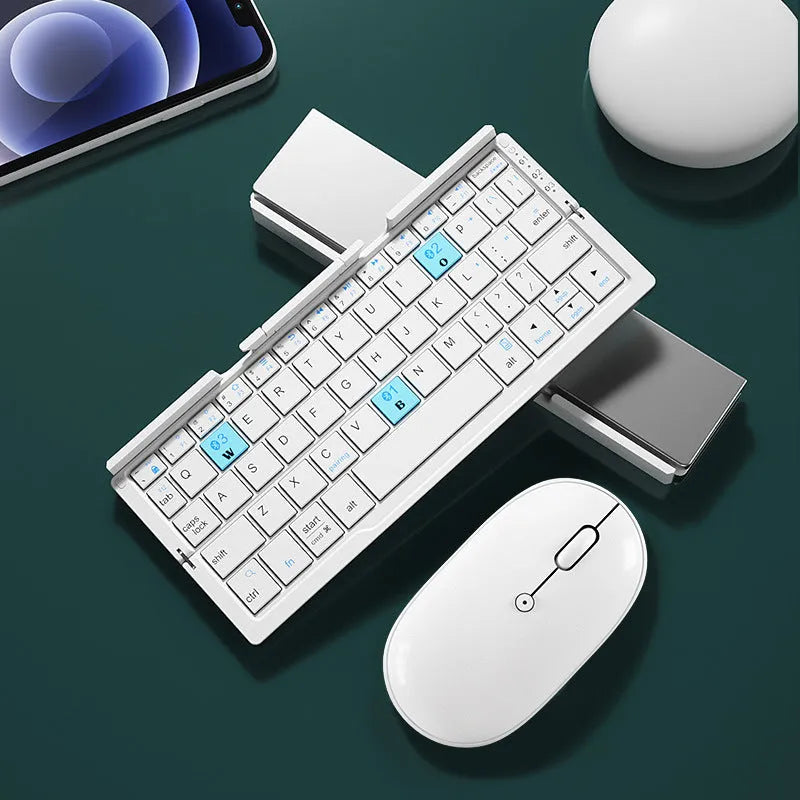 Silver white mini aluminium folding Bluetooth keyboard open next to a smartphone on its integrated stand.