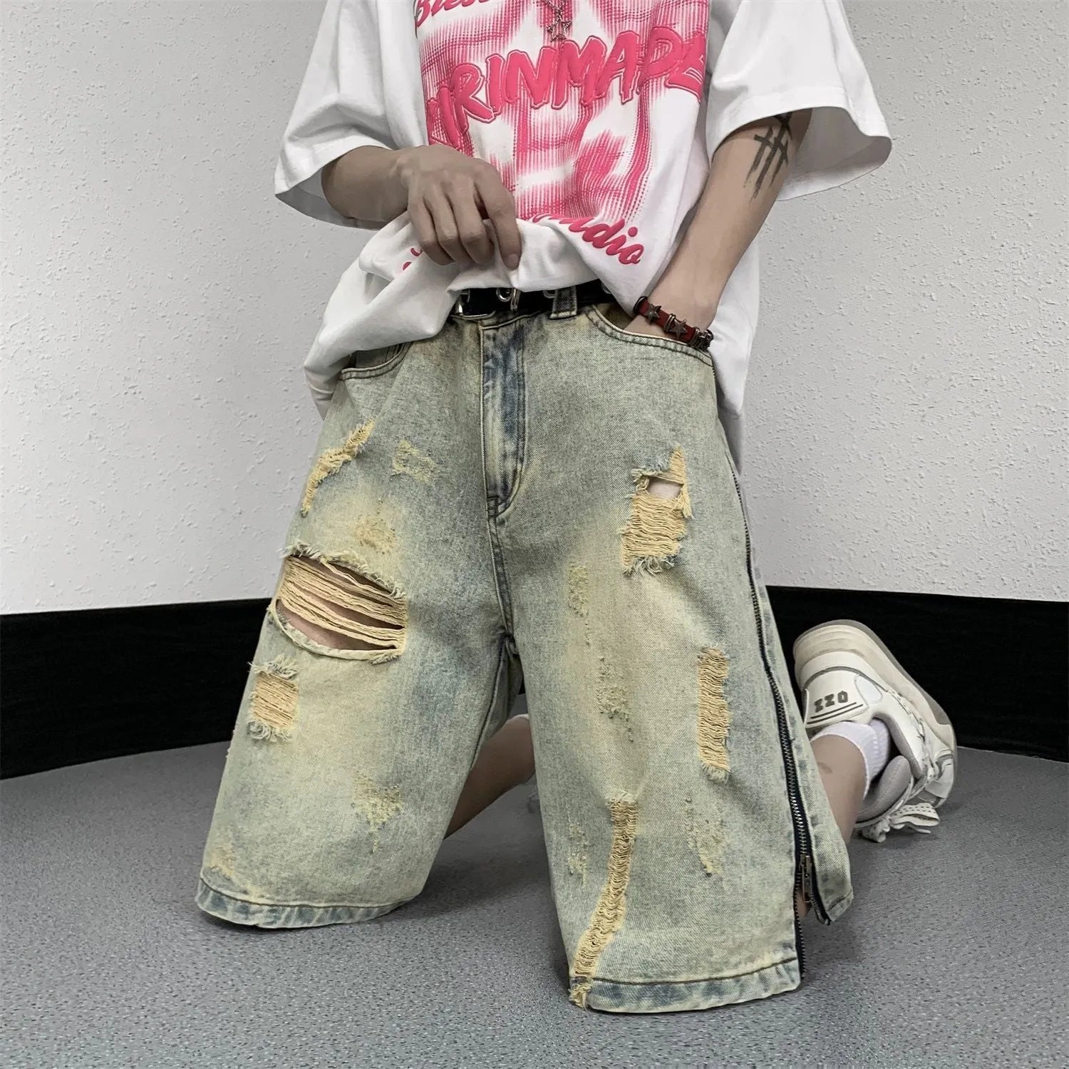 Blue men's loose fit denim shorts with distressed rip details and a yellow mud wash finish.