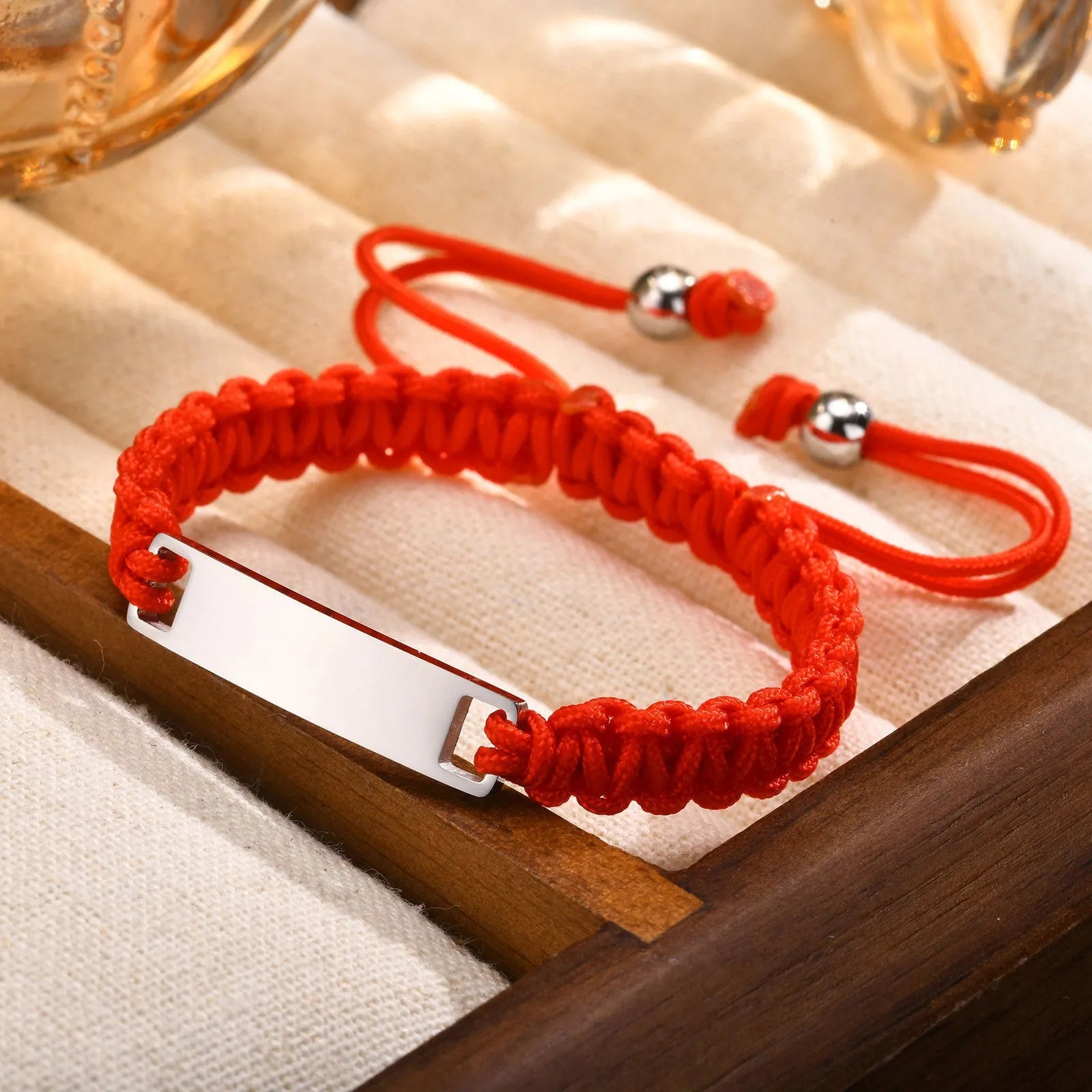 Red nylon rope woven child's bracelet with curved stainless steel brand piece in rose gold finish