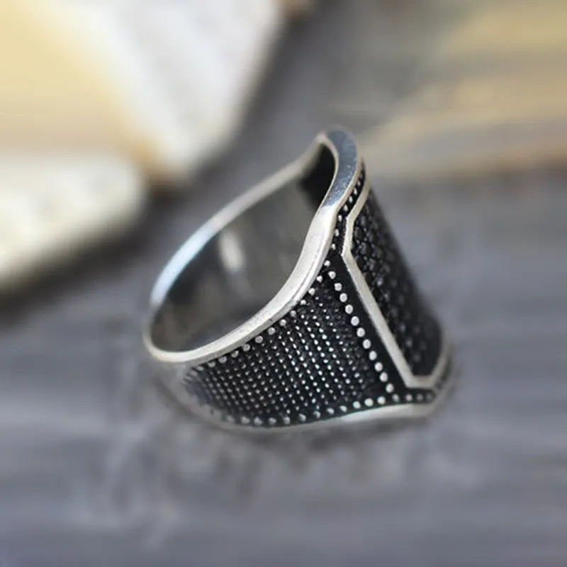 Black alloy ring with copper inlay detail and set zircon stones on a hand.