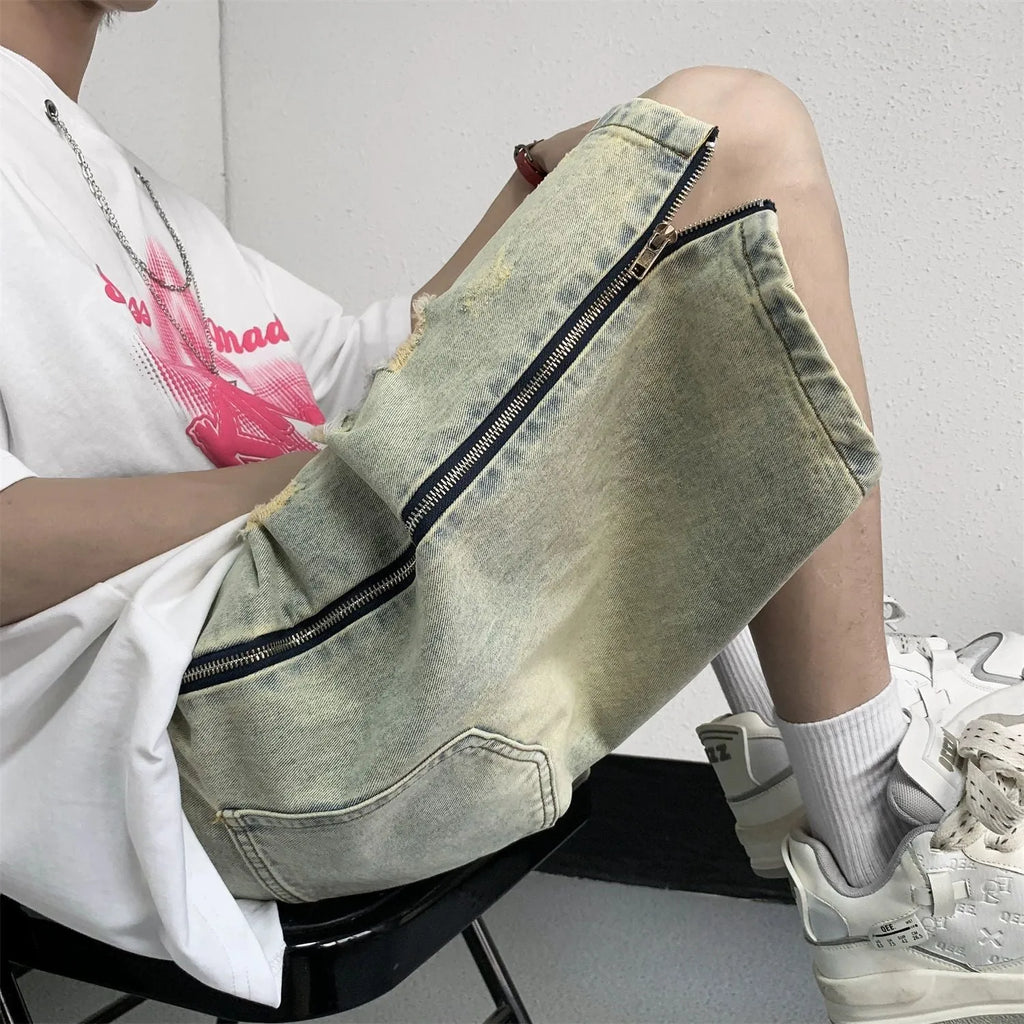 Blue men's loose fit denim shorts with distressed rip details and a yellow mud wash finish.