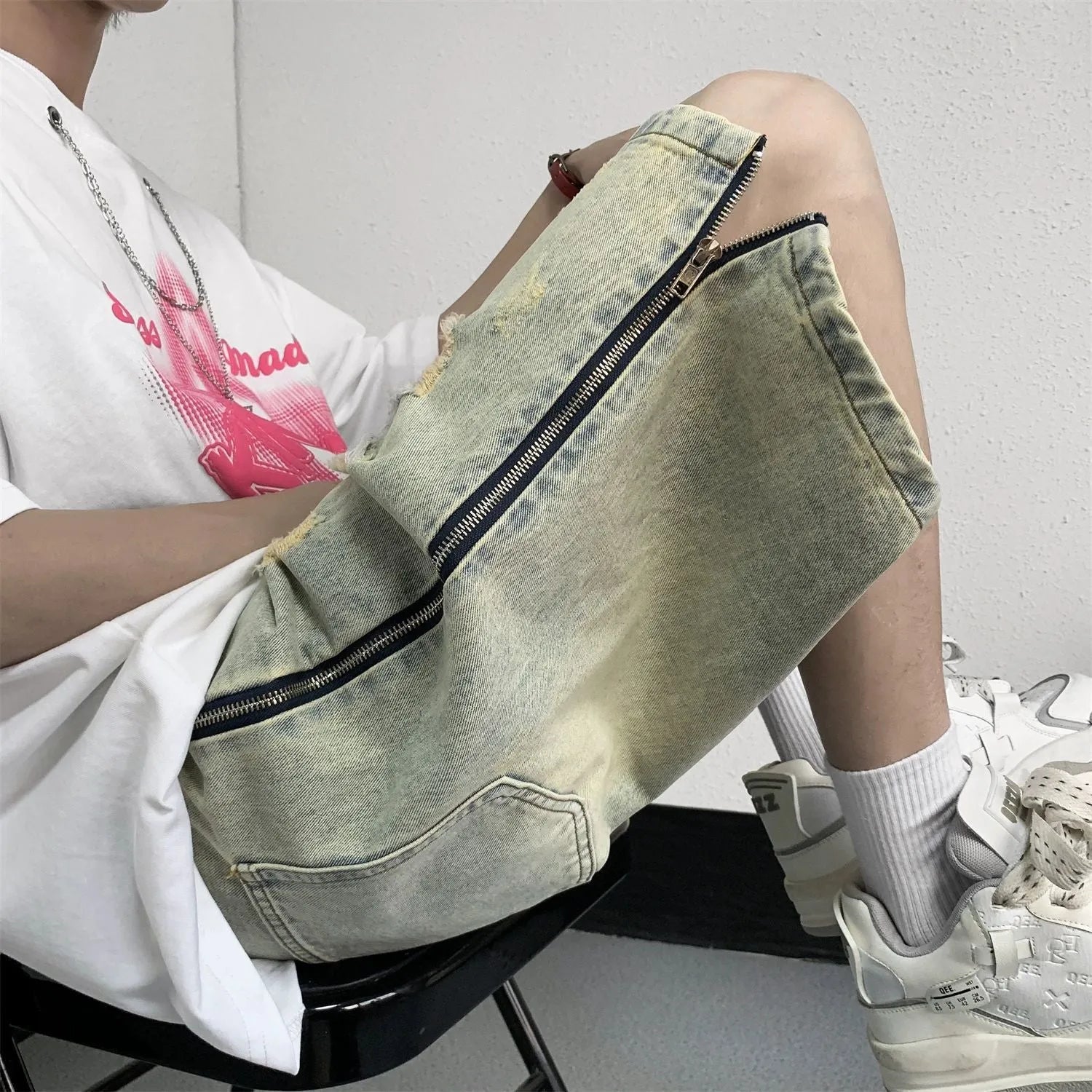Blue men's loose fit denim shorts with distressed rip details and a yellow mud wash finish.