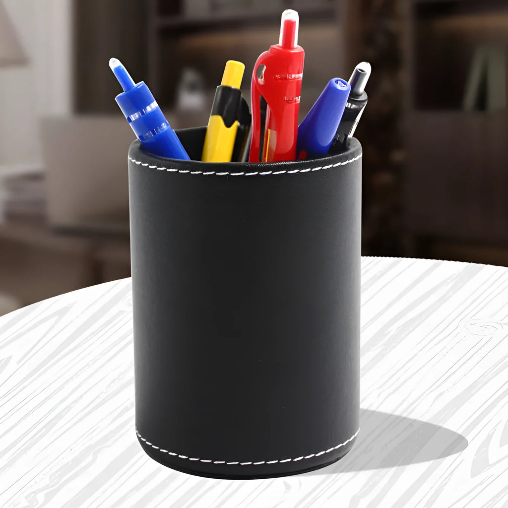 Small round black leather pen container on desk with pens inside