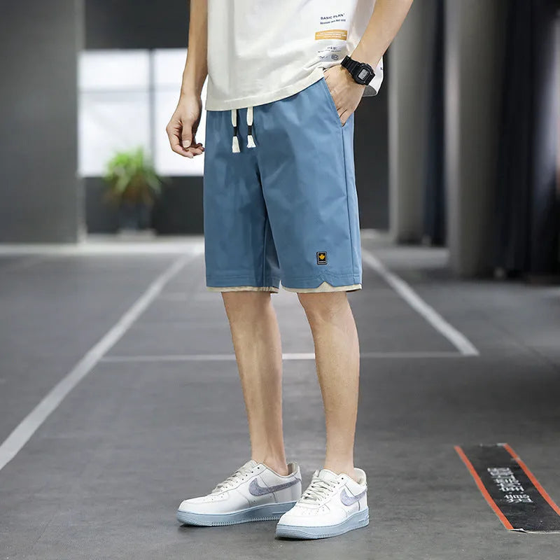 Man wearing straight loose fit beach shorts in 8905 green, made from micro elasticity polyester fabric.