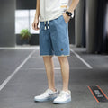 Man wearing straight loose fit beach shorts in 8905 green, made from micro elasticity polyester fabric.