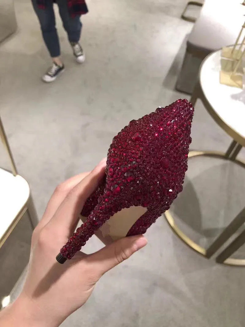 Gold women's pointed toe high heels with rhinestone and bow decoration on a stiletto heel.