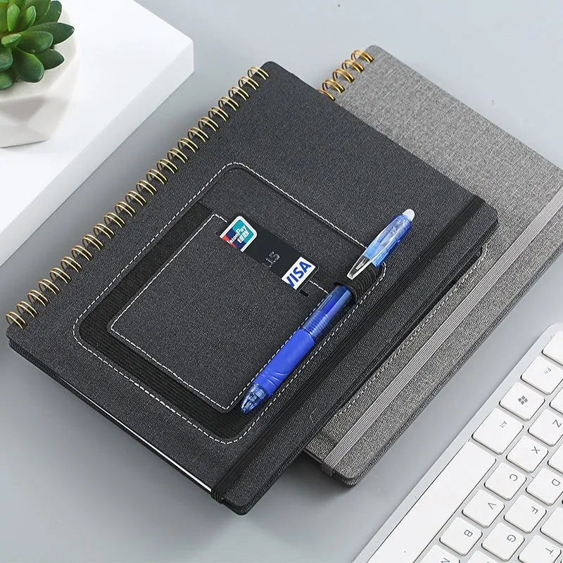 Erasable coil notebook with custom cover on thick waterproof stone paper, shown with pen and cloth.