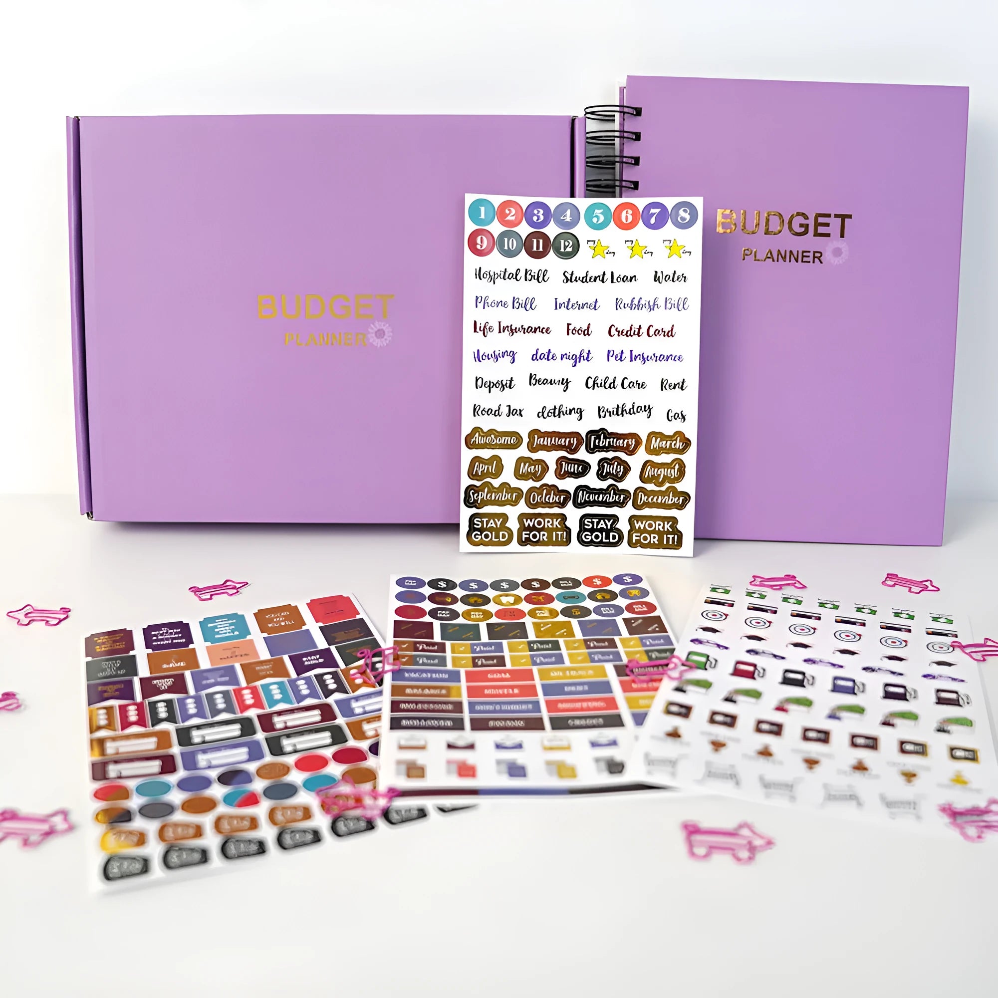 Purple coil-bound budget notebook with pen and stickers for financial planning