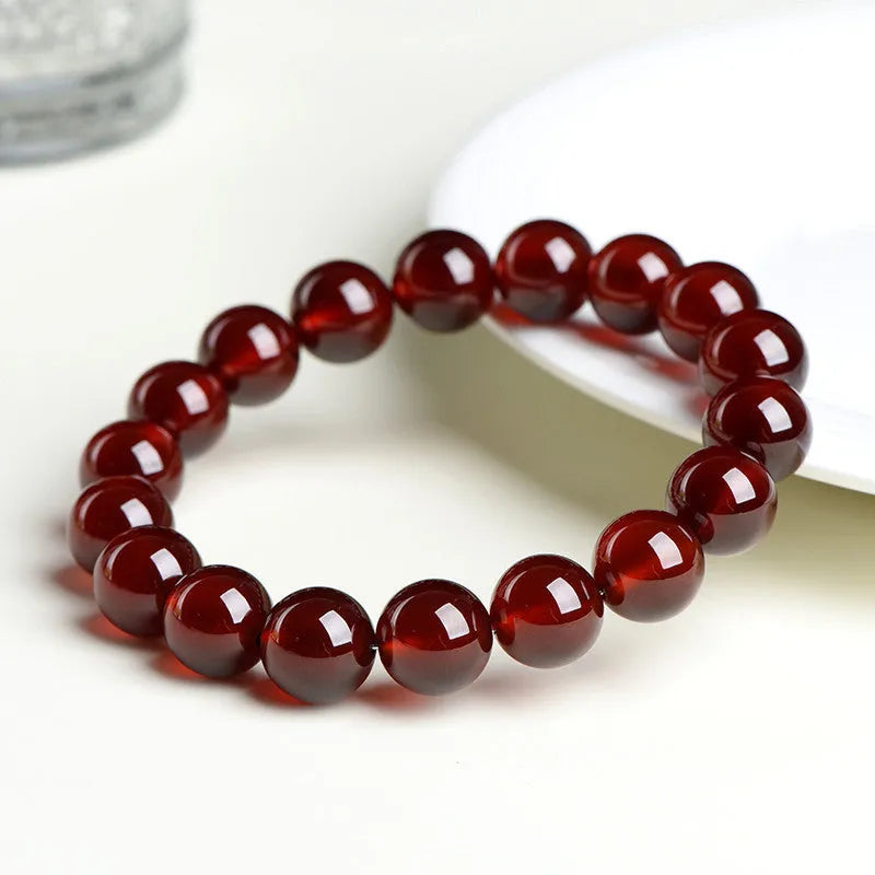 Natural orange red garnet ball bracelet with Ruyi beads on a wrist, showing unisex retro crystal jewellery.