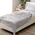 Blue cooling blanket with double-faced texture on a bed, showing its lightweight drape.