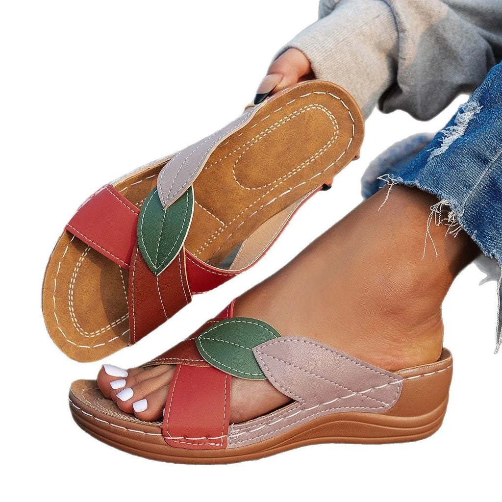 Women's black slippers with thick soles and cross-straps, showing peep-toe design.