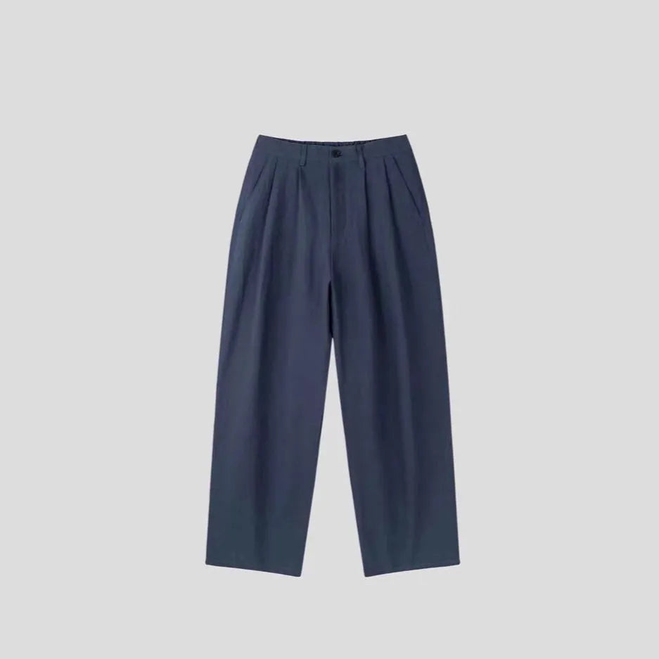 Man wearing loose apricot wide-leg cotton linen blend trousers with a pencil-leg opening.