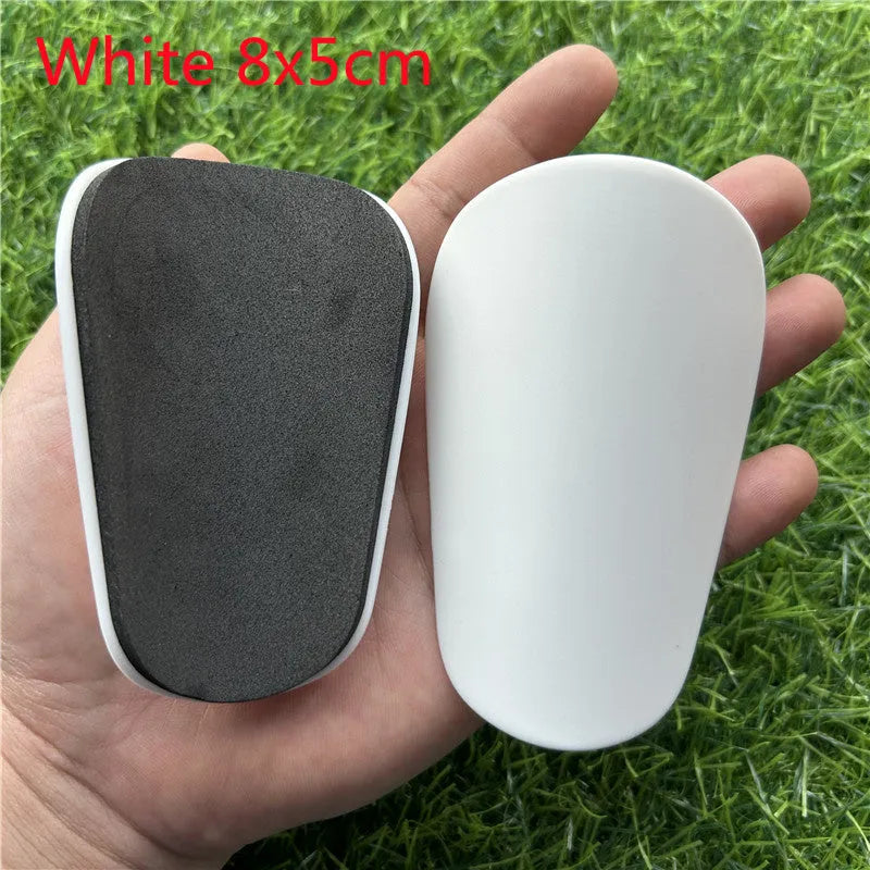 Extra small mini plastic football shin guards for kids in black and white, measuring 8 by 5 centimetres.