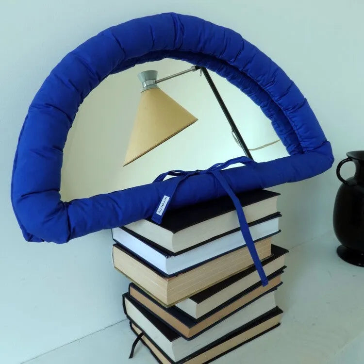White cotton-filled PVC fabric mirror hanging on wall measuring 23x40x5cm