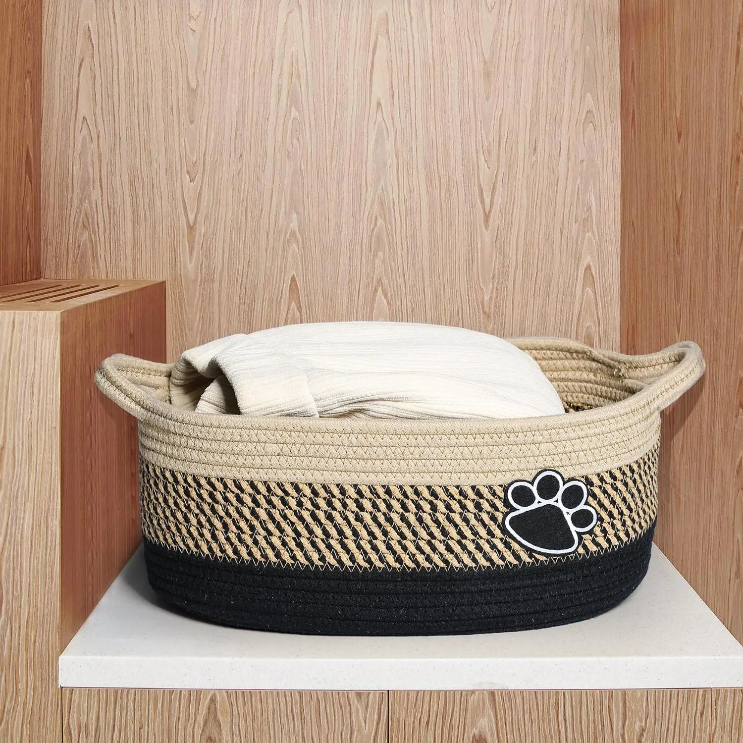 Light beige handmade cotton rope storage basket with wooden base and handle on a wooden floor