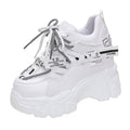 Women's white mesh platform trainers with cross-strap and chunky rubber sole on a neutral background.