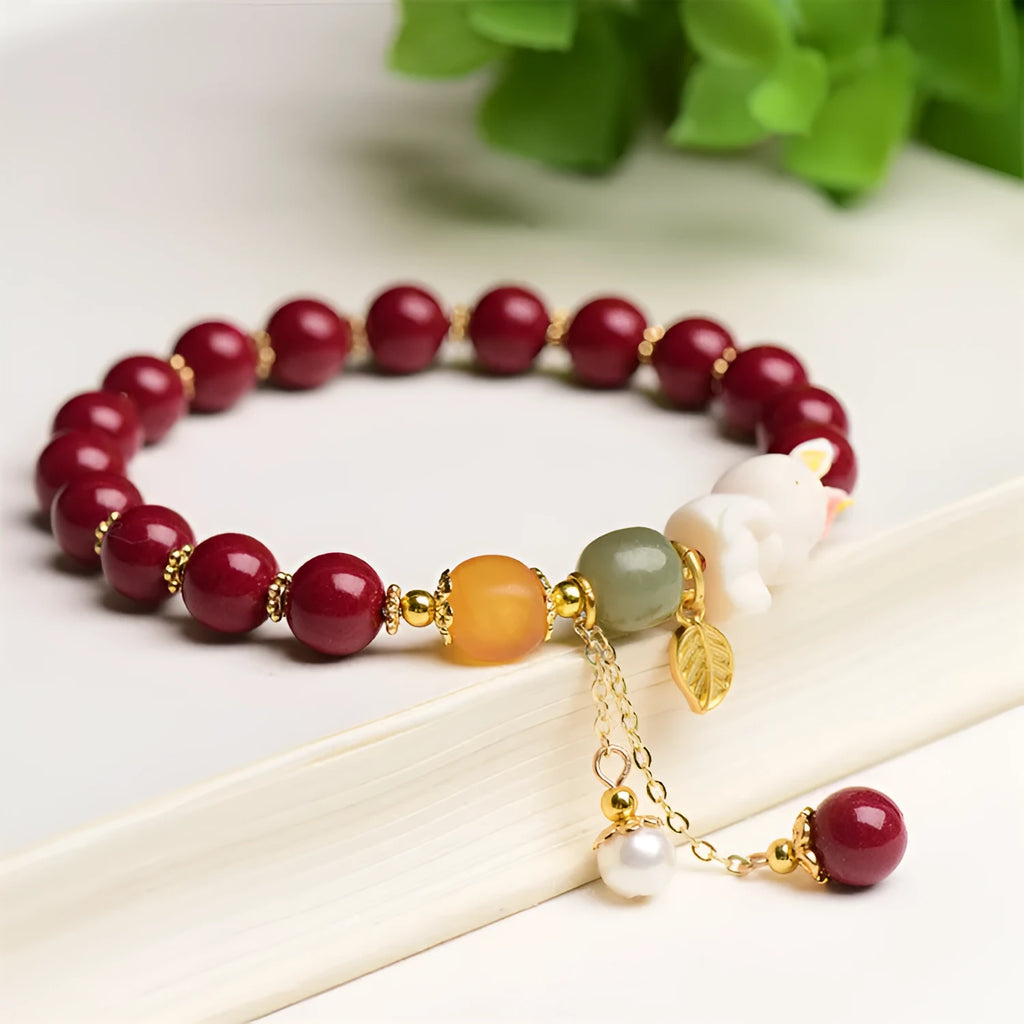 Natural cinnabar bracelet with hand-carved rabbit charm and metallic accents in deep purple-red colour