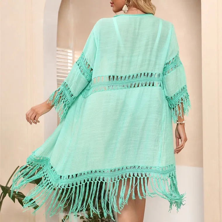 A woman's hand-crocheted acrylic beach cover-up cardigan with tassel details, shown in water green colour.