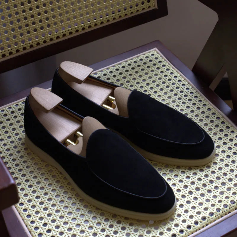 British handmade men's brown genuine leather flat loafers on a plain background.