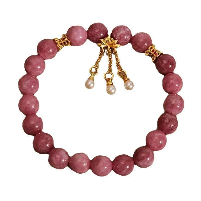 Close-up of a women's natural stone bracelet with a pink lotus tassel and pink white crystal electroplated flower pendant.