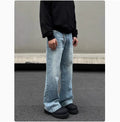 Man wearing blue straight leg jeans with whisker wash detailing and a flared leg style.