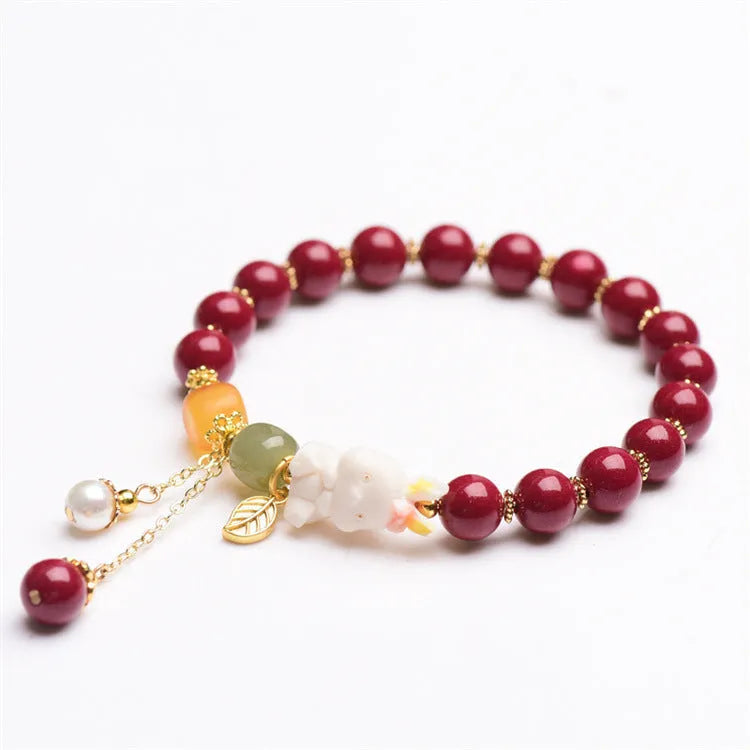 Natural cinnabar bracelet with hand-carved rabbit charm and metallic accents in deep purple-red colour