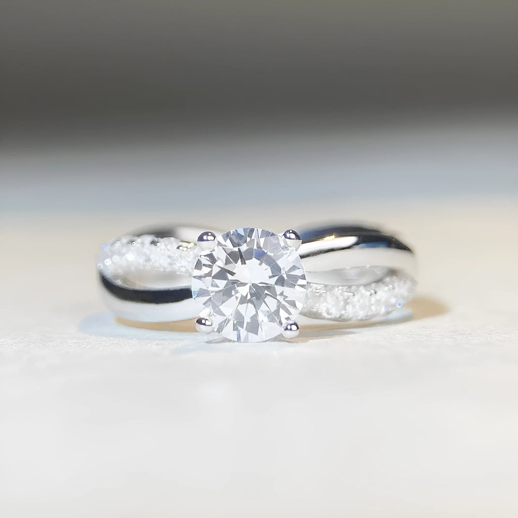 Silver geometric ring with a twisted band, a cross design, and a 1 karat moissanite in a four-claw setting.