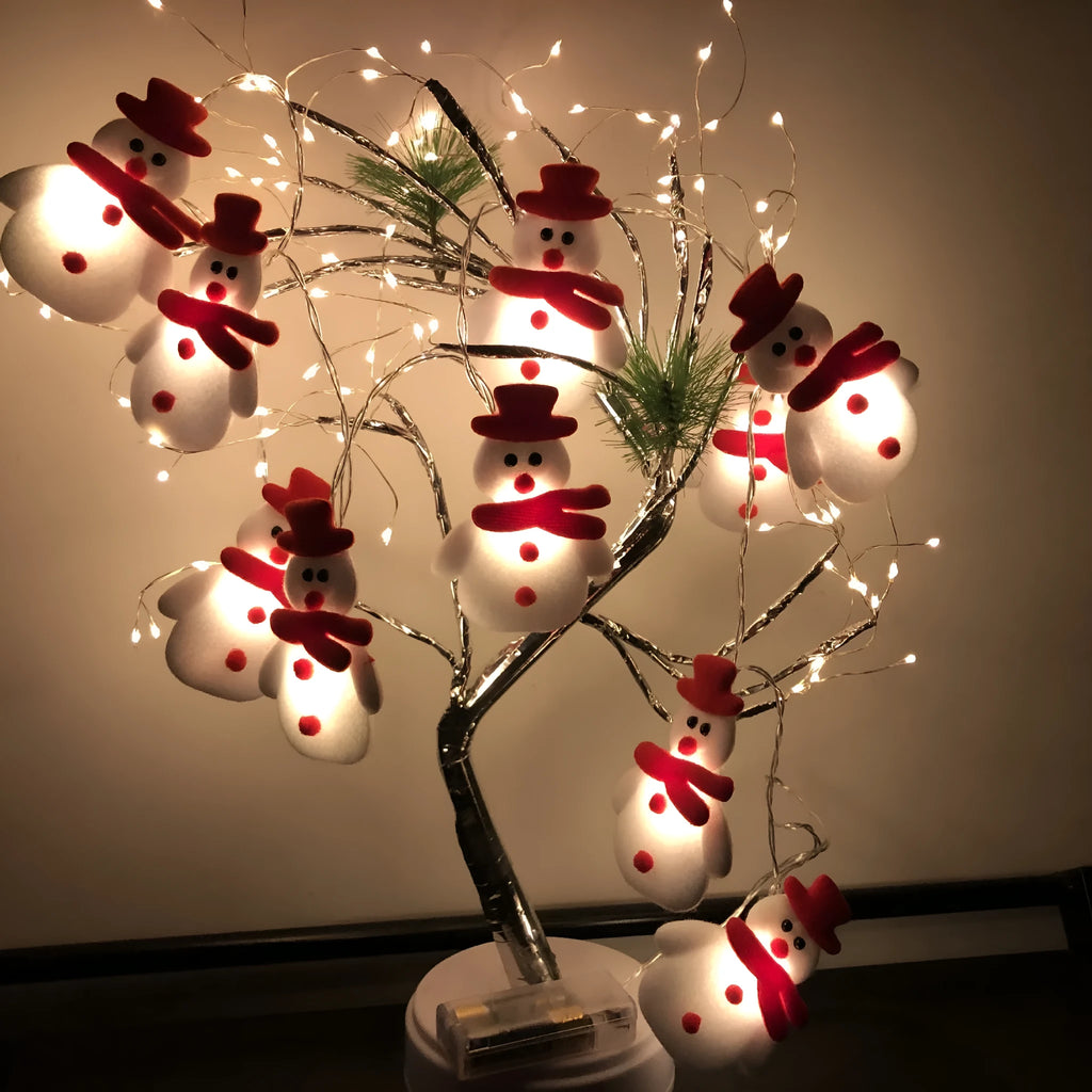 Close-up of warm white Christmas LED string lights with integrated snowman decoration on a green wire garland