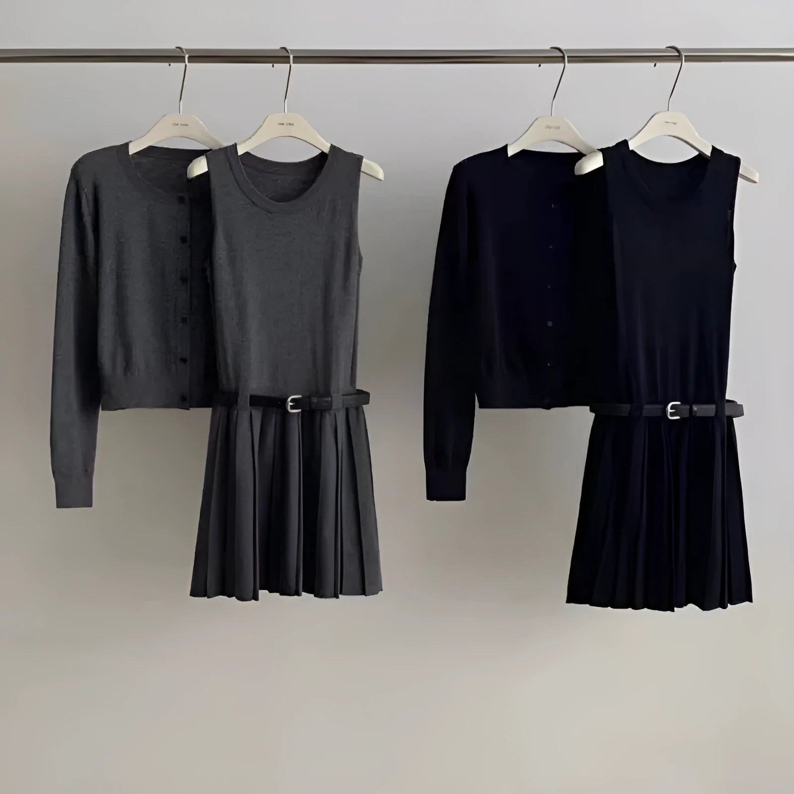 Women's black knitted two-piece set showing vest skirt with belt and long-sleeved cardigan with 3D pattern