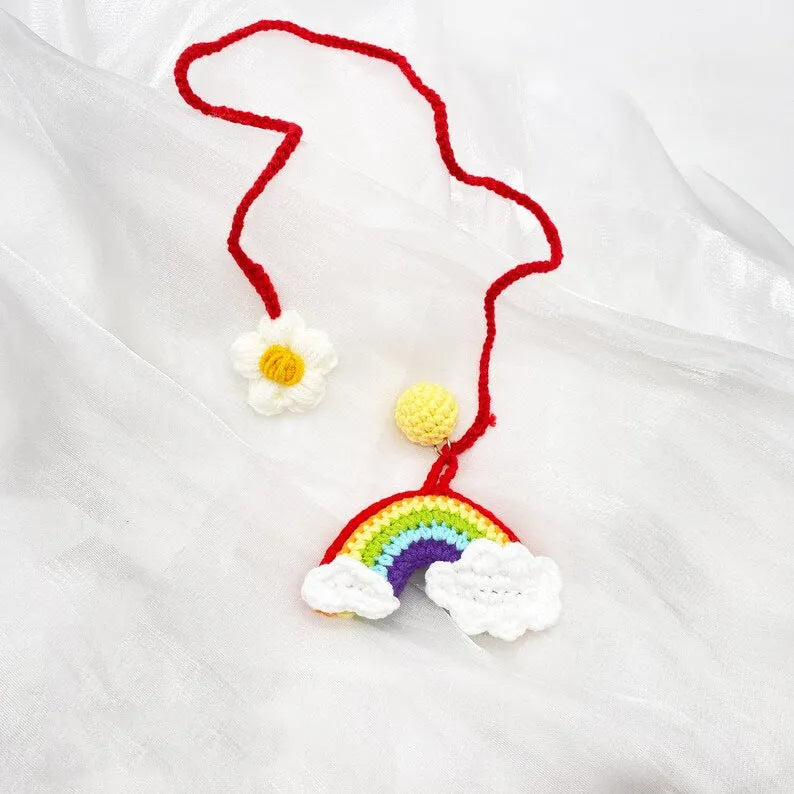 Handmade crocheted car pendant featuring a colourful avocado and rainbow flower design in wool yarn.