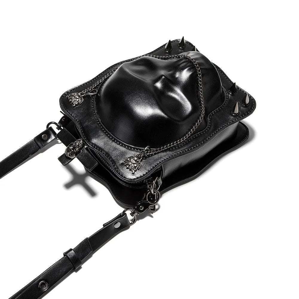 Black gothic mini square messenger bag with skull embossing, stitching, rivets, and chain details on textured PU polyester