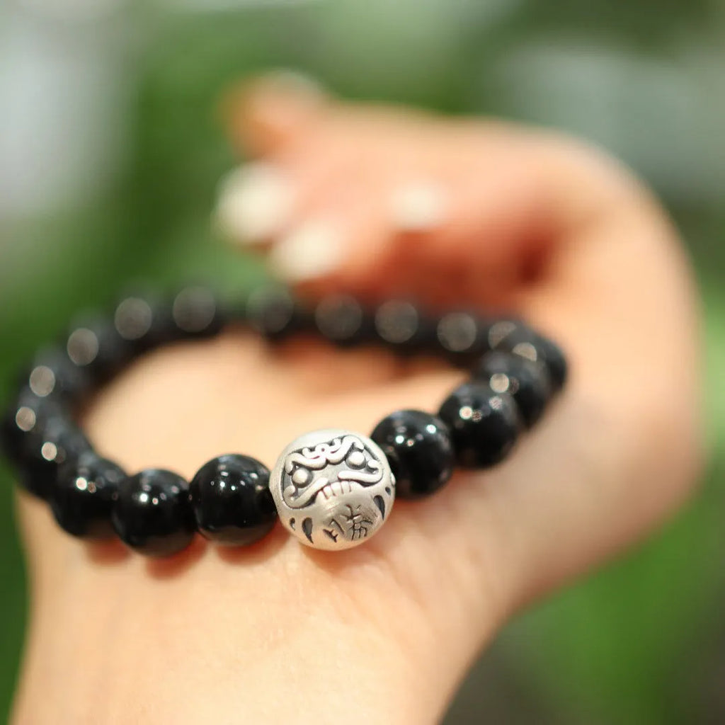 Close-up of a black agate beaded bracelet with a sterling silver clasp on a wrist.