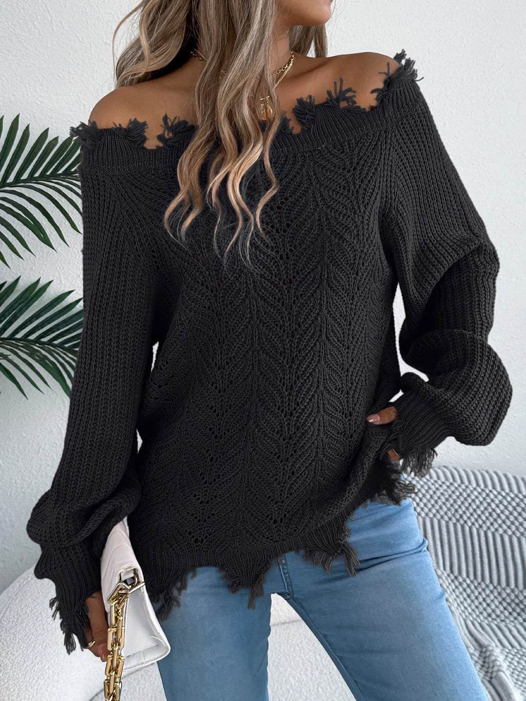 White hollow-out off-the-shoulder long-sleeve pullover sweater laid flat.