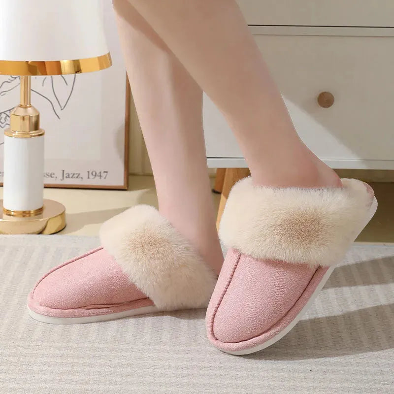 Women's plush winter slippers in pink with a round toe, flat heel, and decorative stitching.