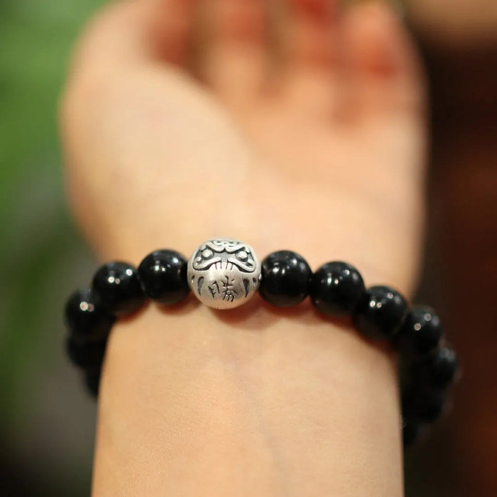 Close-up of a black agate beaded bracelet with a sterling silver clasp on a wrist.