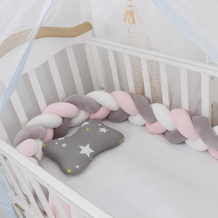 Braided knot design crib bumper in spandex velvet, shown in a light grey colour wrapped around crib slats.