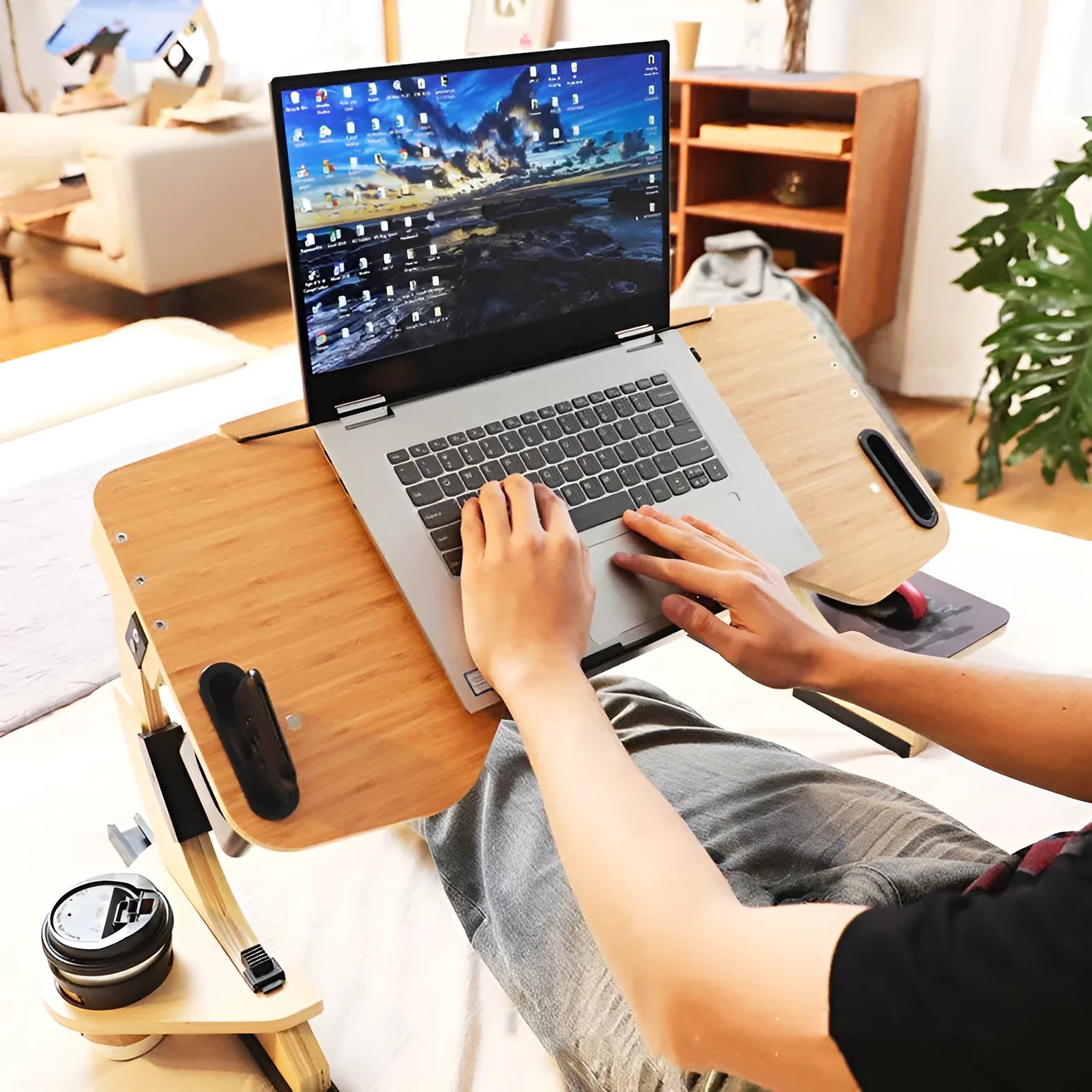 Wooden folding laptop table on a bed with adjustable angle, shown in white maple finish.