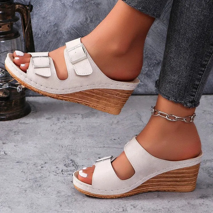 Women's beige wedge heel slippers with a decorative outer buckle fastening on a rubber sole