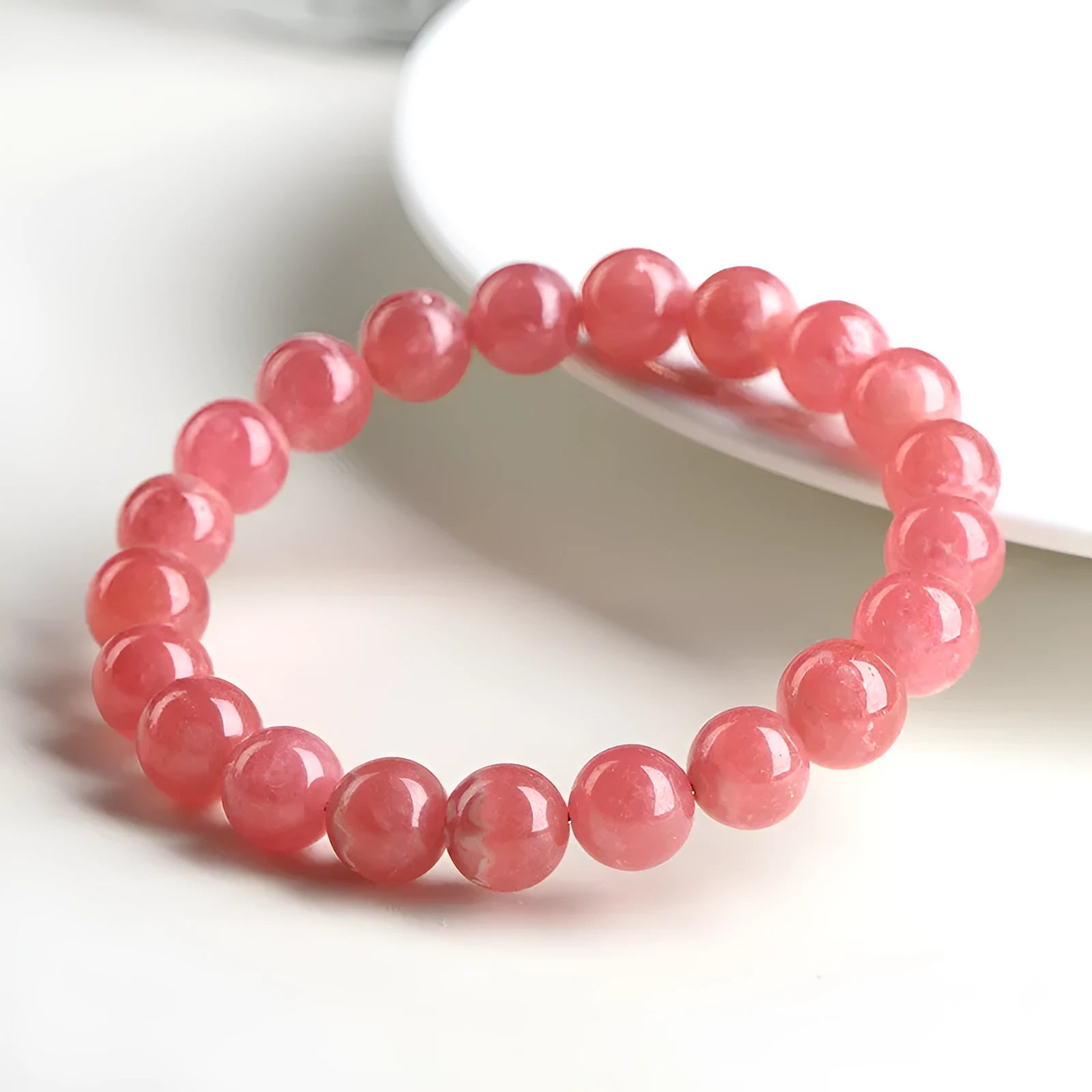 Women's geometric rhodochrosite crystal bracelet with a Longevity Lock design on red beads.