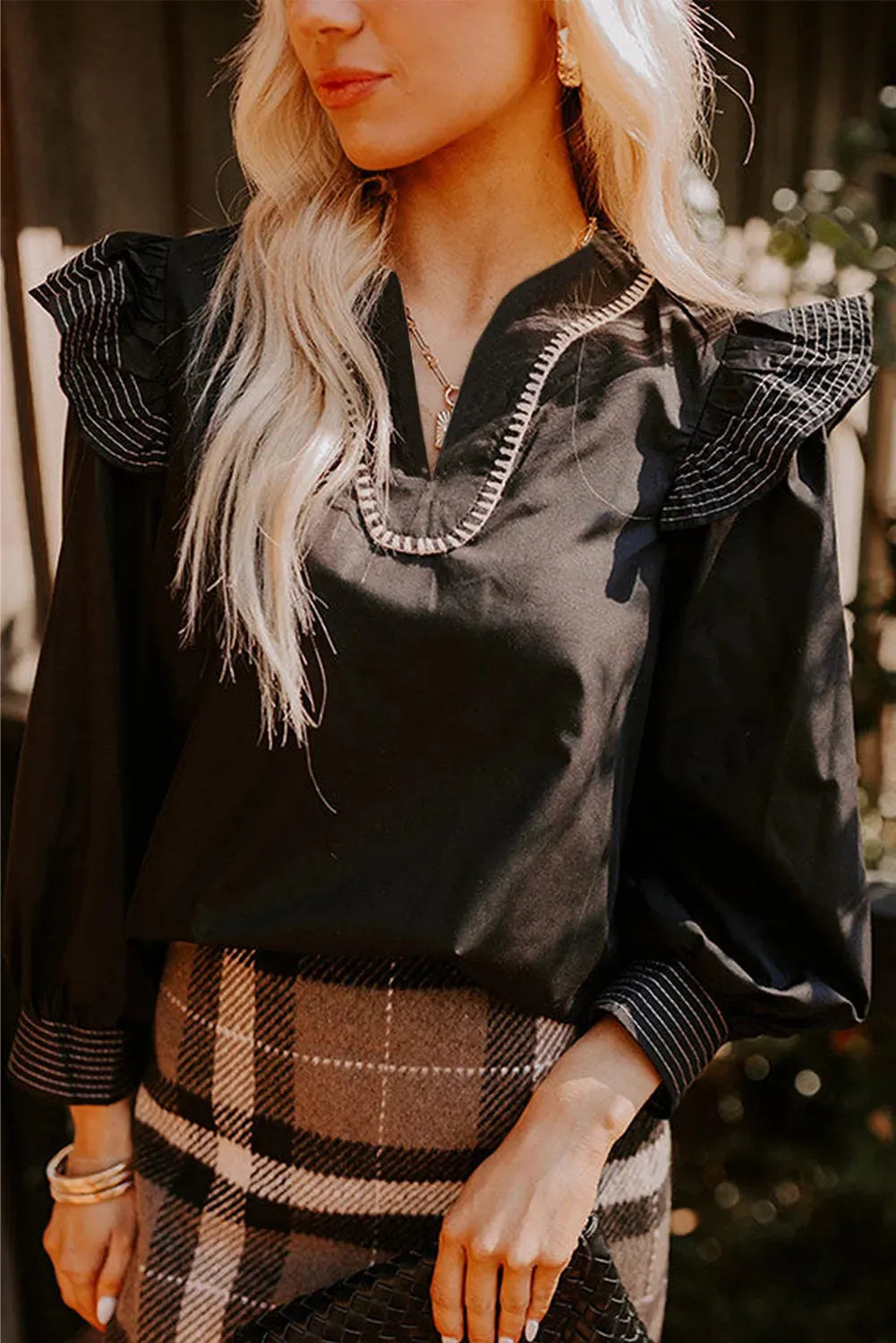 Black women's V-neck blouse with long ruffle sleeves and contrast colour stitching.