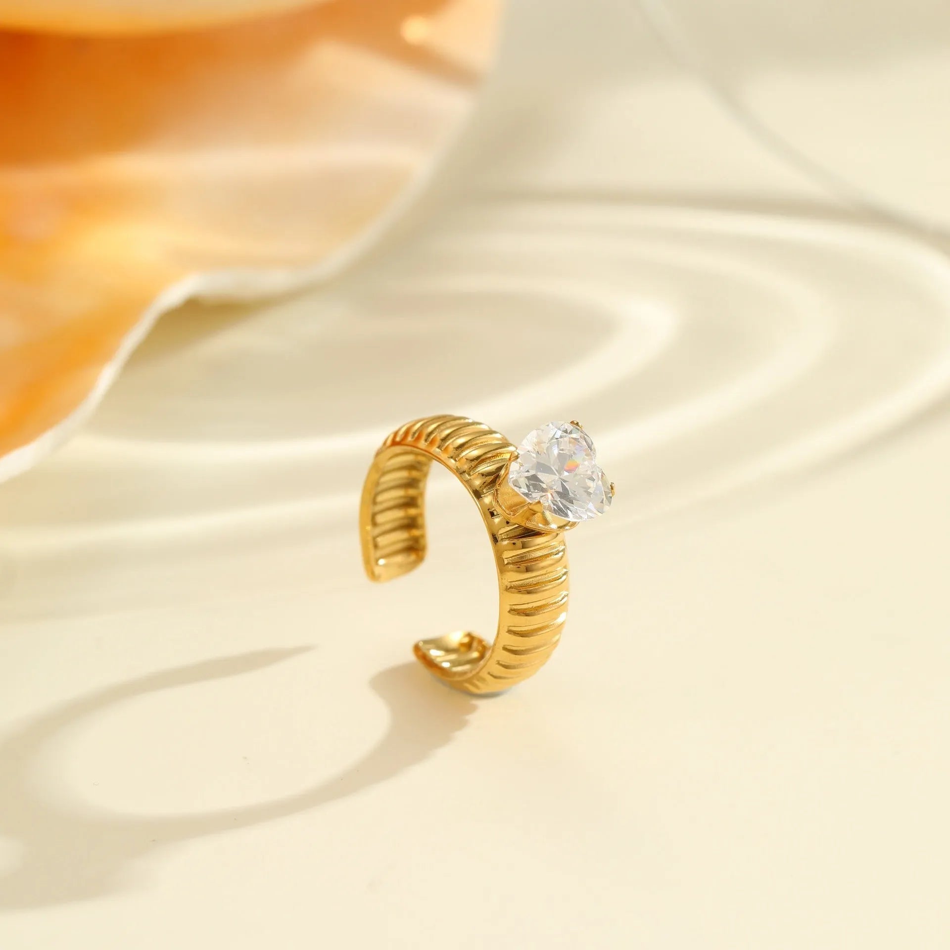 Gold plated stainless steel geometric heart ring with zircon stones and adjustable open mouth design.