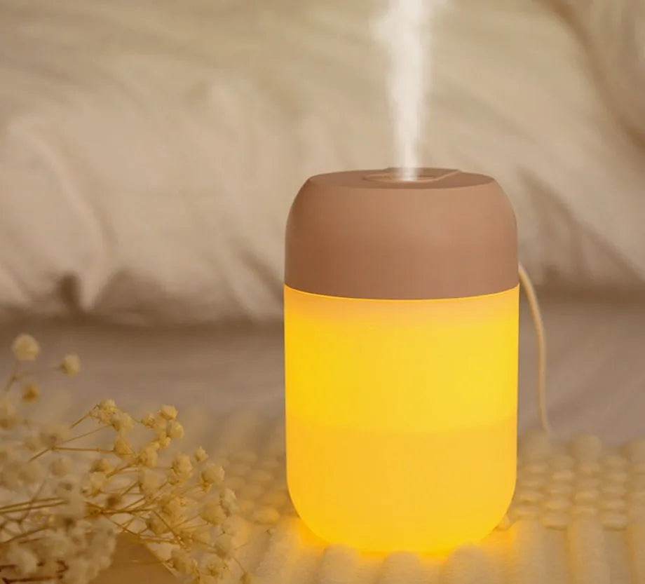 White cylindrical USB-powered mini humidifier with aromatherapy function on a wooden desk.