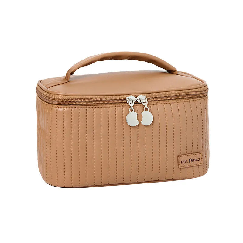 Open-top round pink PU leather makeup bag with a flat bottom on a table.
