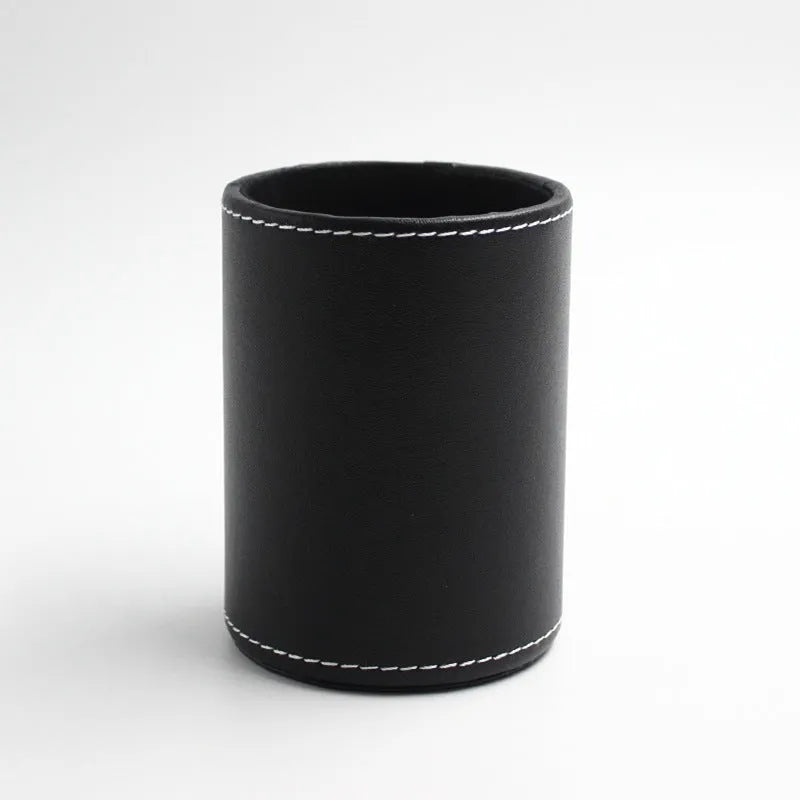 Small round black leather pen container on desk with pens inside