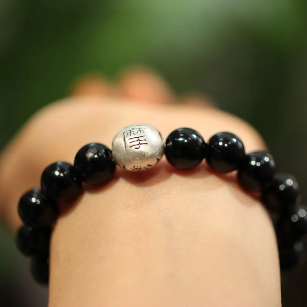 Close-up of a black agate beaded bracelet with a sterling silver clasp on a wrist.