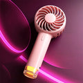 Portable handheld electric fan with colourful mini lamp, round handle, shown in beige, pink, or purple.