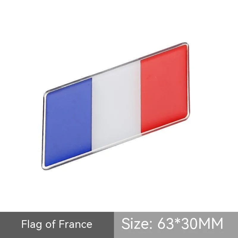 Aluminium national flag car sticker in a parallelogram shape measuring 6.3 by 3 centimetres.