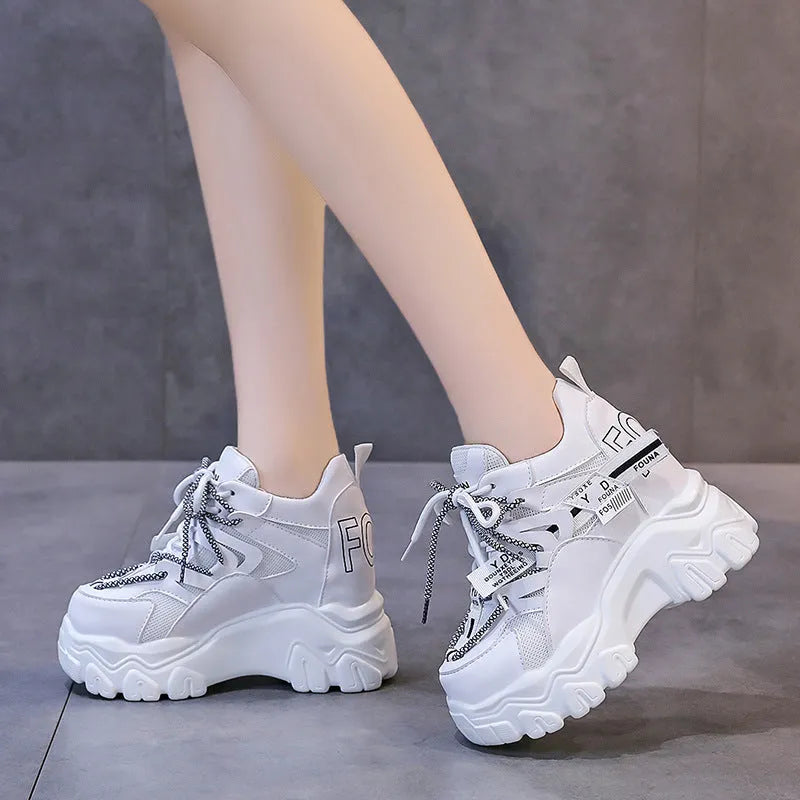 Women's white mesh platform trainers with cross-strap and chunky rubber sole on a neutral background.