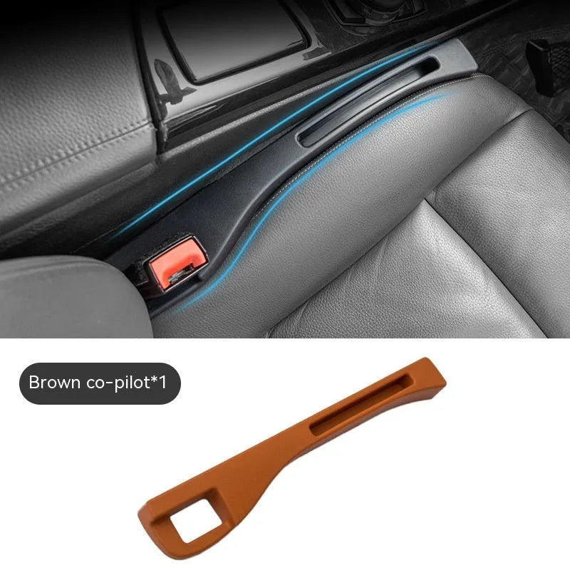 Black plastic car seat gap storage organiser box with a handle, shown inserted between vehicle seats.